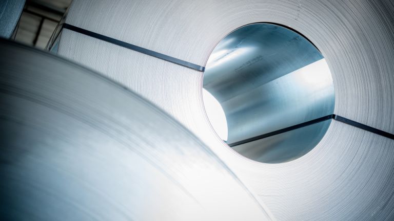 voorraad-gestapelde-rollen-sendzimir-verzinkt-en-zink-magnesium-bandstaal Een voorraad van meerdere rollen nog niet geslitte coils sendzimir verzinkt en zink magnesium staal die op de slitmachine geslit gaan worden tot bandstaal.