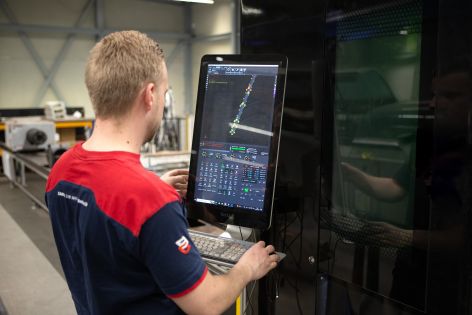 Productiemedewerker bedient een lasermachine op de productielocatie Productiemedewerker bedient een lasermachine op de productielocatie