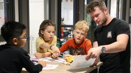 Kinderen kijken naar een tekening met een leraar.