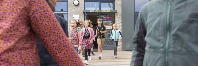 Kinderen rennen de school uit.