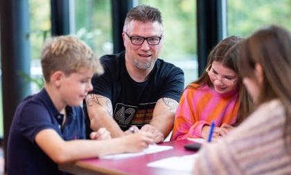 Docent aan een tafel met drie leerlingen