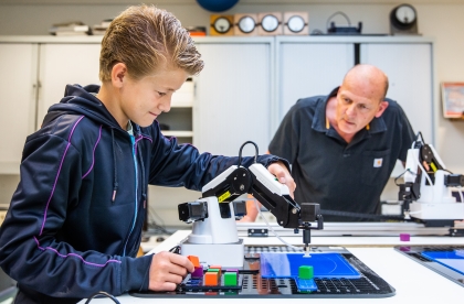 Een leerling en docent werken met een robot