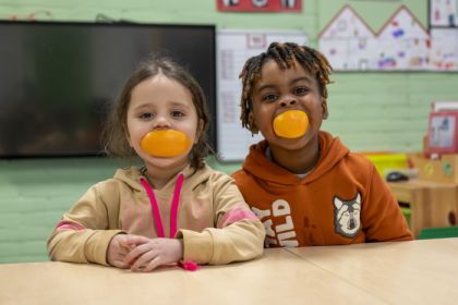 kinderen lachen met sinaasappel in hun mond