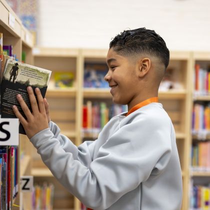 kind zet boek in kast