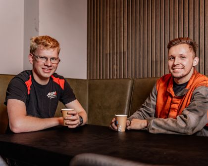 Twee collega's van mouw hoedliggers drinken samen een bakje koffie en kijken de camera in