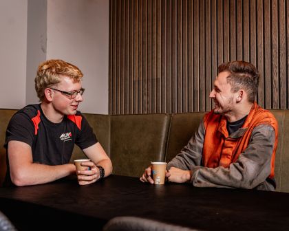 Twee werknemers van Mouw Hoedliggers drinken koffie en kijken elkaar aan