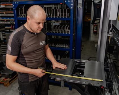 man staat met meetlint bij metalen plaat