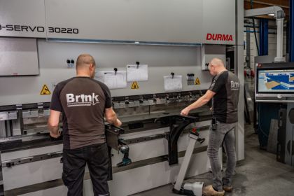 Twee kanter/zetters zijn bezig met het zetten van metalen platen