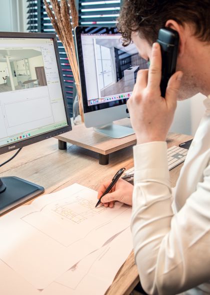 Werkvoorbereider aan het bellen achter zijn bureau waar een computer aanstaat