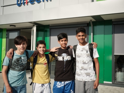 Vier leerlingen staan voor de voordeur van het schoolgebouw van ISUtrecht