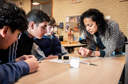 Docent helpt een groepje van vier leerlingen