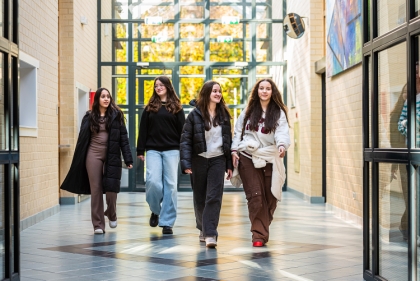 Vier leerlingen lopen door de gang van het schoolgebouw.