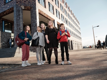 Een groep leerlingen staat voor het schoolgebouw.