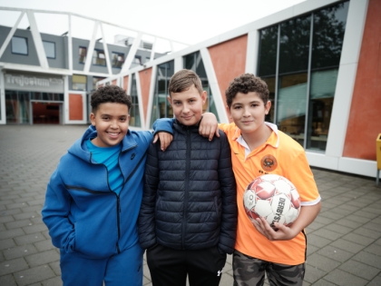 Drie jongens staan op het schoolplein