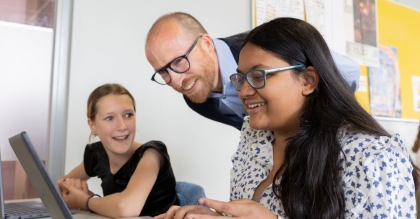 Leerlingen met leraar kijken samen naar een laptop