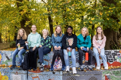 Leerlingen zitten buiten op een bankje