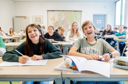 Decoratief. Een klaslokaal met leerlingen. Twee leerlingen vooraan met open schrift.