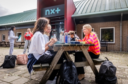Leerlingen brengen hun pauze door aan een picknicktafel voor de school