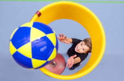 Bovenaanzicht van een korfbalkorf waar een bal in gegooid wordt door een leerling