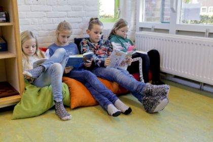 Meiden lezen op zitzakken in school.