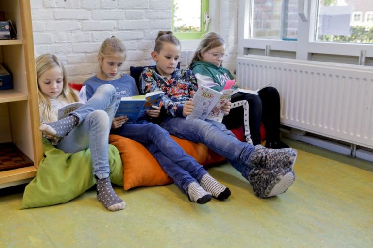 Meiden lezen op zitzakken in school.