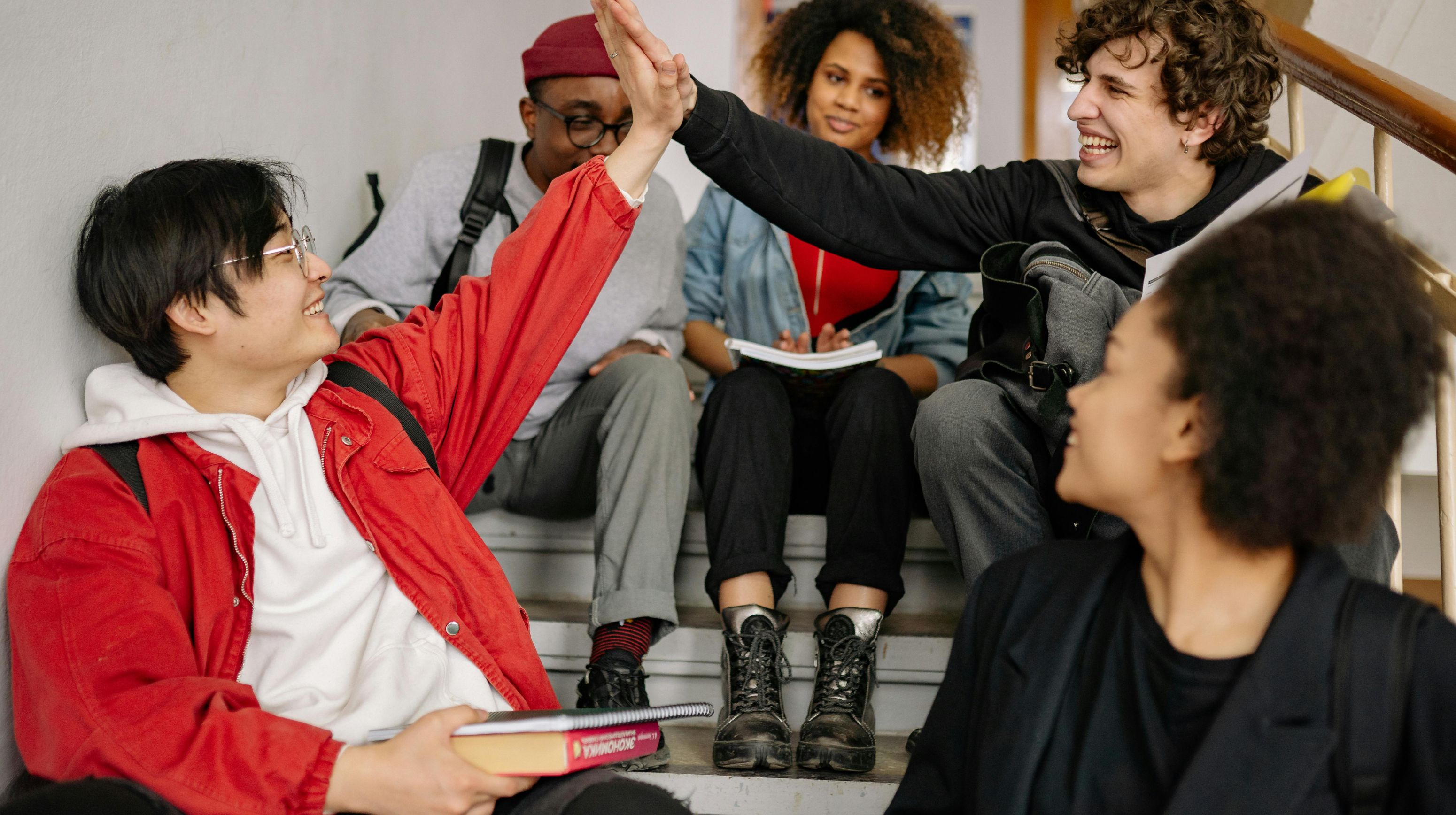 leerlingen zitten op trap en geven high five