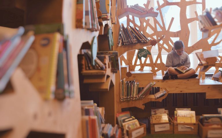 Een kind leest een boek in de schoolbib