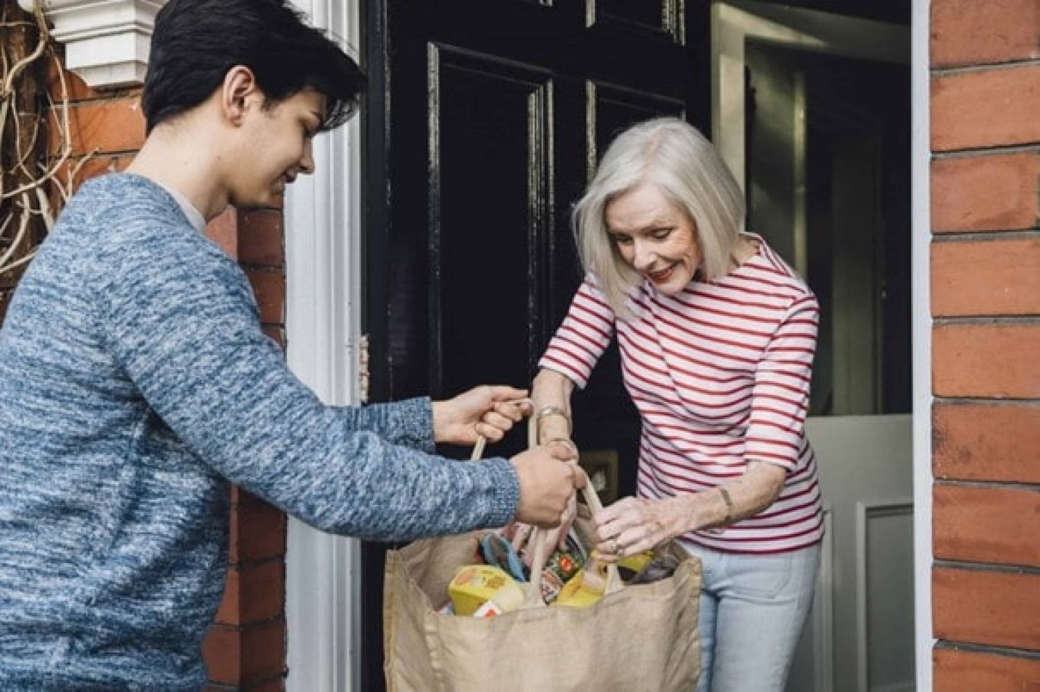 Jonge vrijwilliger doet boodschappen voor oudere mevrouw
