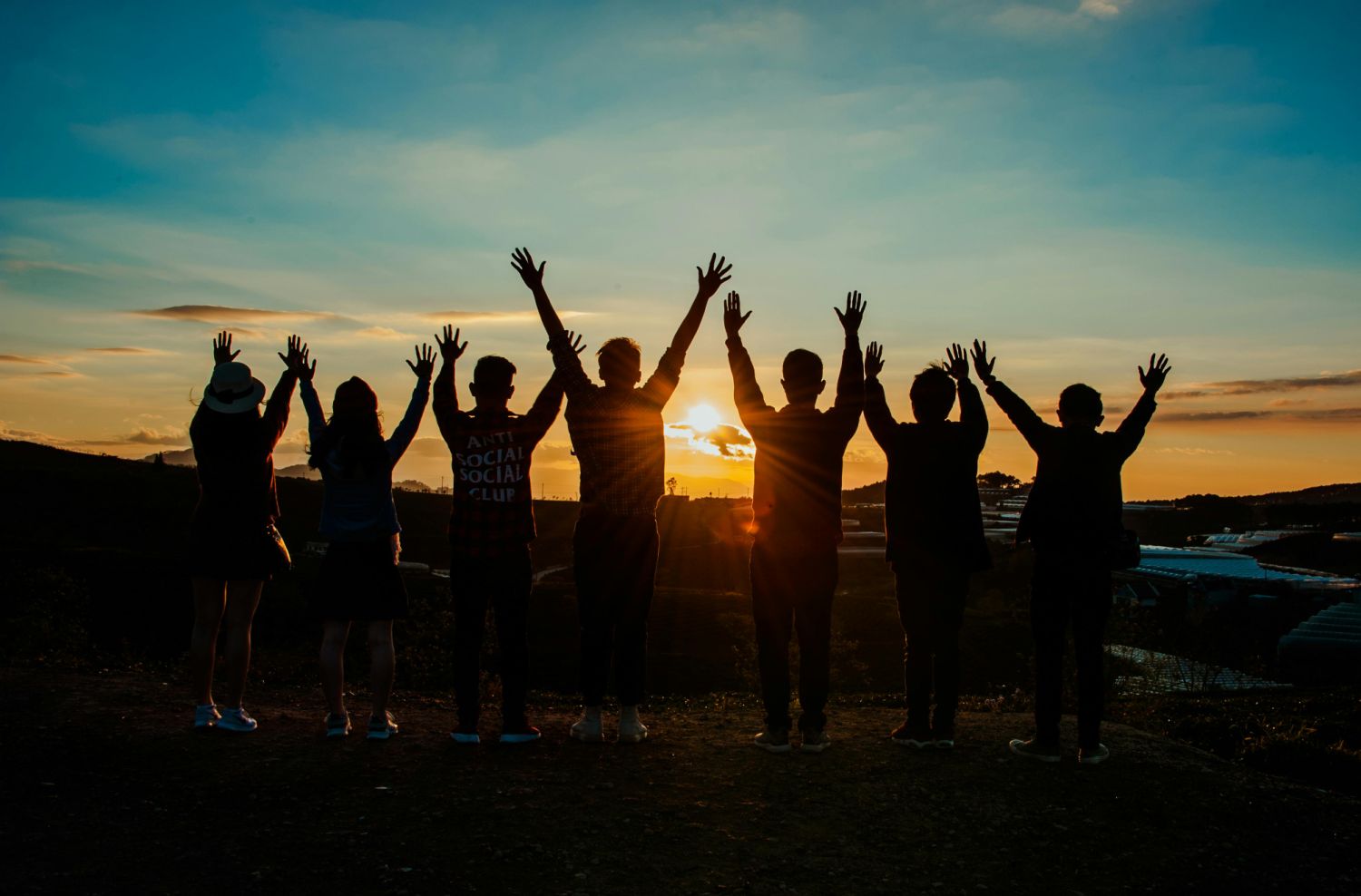 Groep mensen juicht tijdens zonsondergang