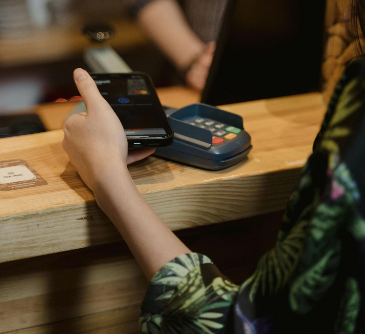 Een jonge vrouw houdt haar pinpas voor pinapparaat om te betalen