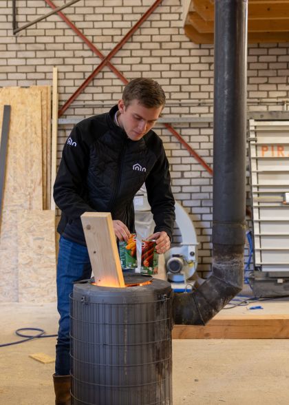Timmerman is bezig met knakworsten opwarmen op een ijzeren ton
