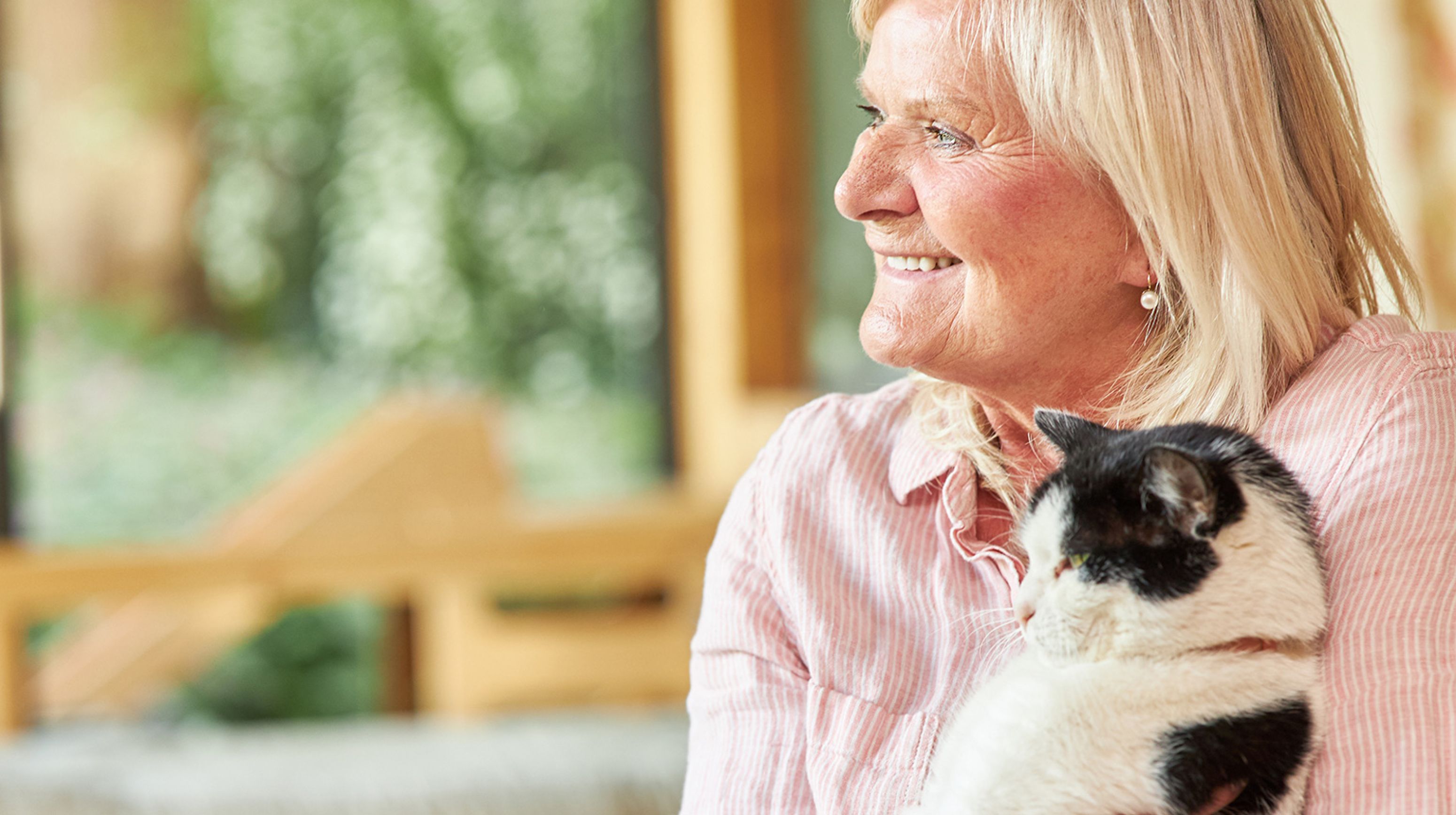 Ouder dame met zwart witte kat op haar arm