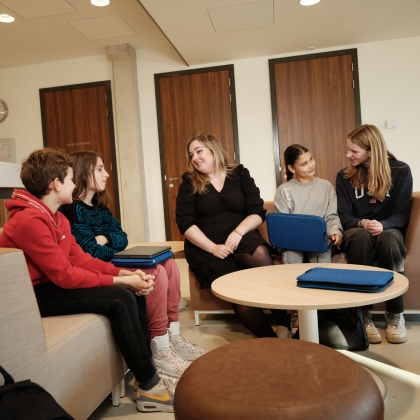 Foto van een docent op de trap van het Academie Tien gebouw. Hij kijkt vrolijk en ontspannen in de camera.