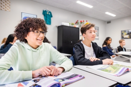 Leerlingen zitten aan picknicktafel op schoolplein met lunch