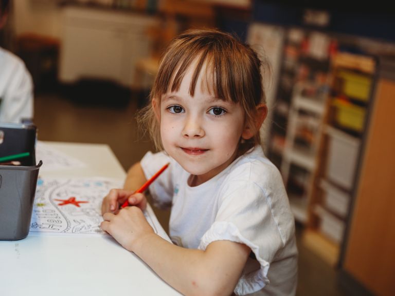 Young girl holding a red pencil for coloring, smiling directly at camera Young girl holding a red pencil for coloring, smiling directly at camera