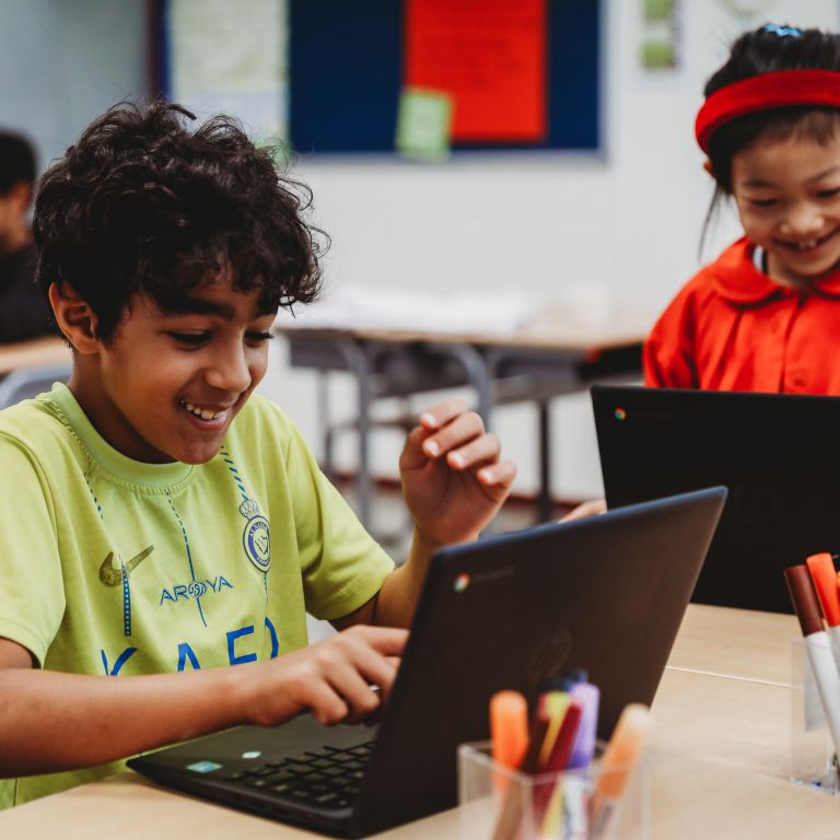 Young boy in classroom using laptop Young boy in classroom using laptop