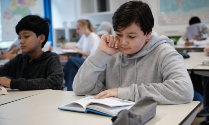 Leerling die in zijn leerboek kijkt.