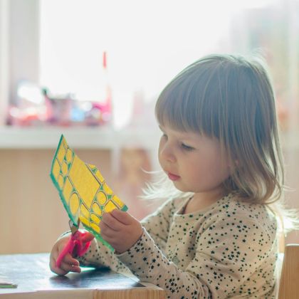 Jong meisje aan het knutselen met papier en schaar