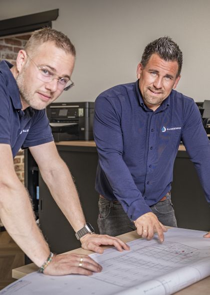 Gezellige Collega's, twee collega's van DI Koeltechniek bekijken een tekening en kijken in de camera