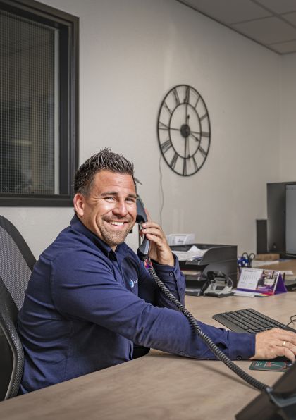 Planner kijkt richting de camera met een telefoon aan zijn oor