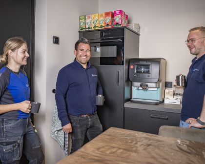 Medewerkers van DI Koeltechniek staan bij het koffiezetapparaat en kijken richting de camera