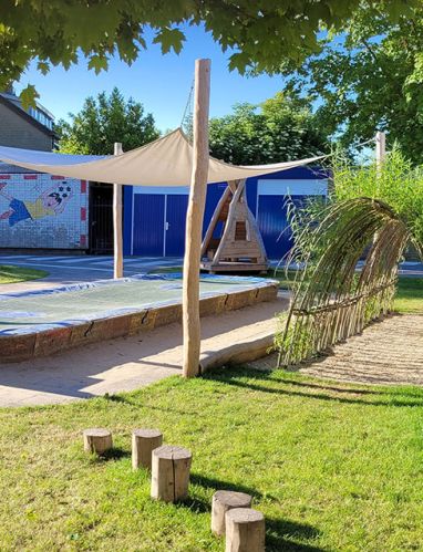 Kleine plein Groene kleine plein met zandbak, schaduwdoek en houten hut
