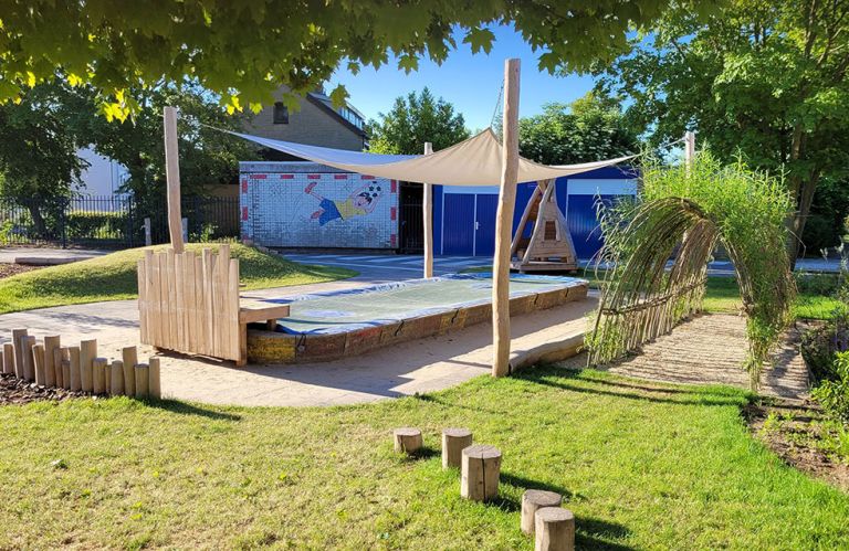 Kleine plein Groene kleine plein met zandbak, schaduwdoek en houten hut