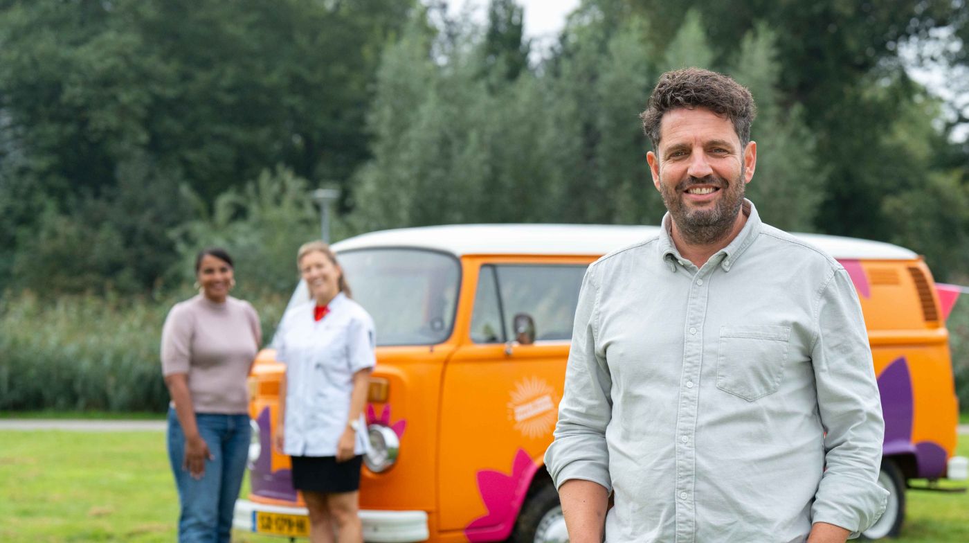 Hulpverlener hulpverlening vacature bus vol waardering Ronald den Deurwaarder campagne werving management zonderuniform christelijk Man poseert voor oranje volkswagenbus in het park