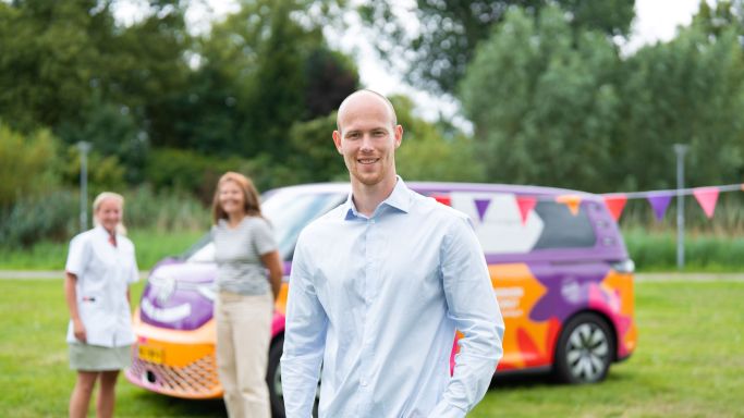 Werving vacature collega bus vol waardering Rijnmond behandelaren hoofdweg christelijke zorgorganisatie Lelie zorggroep Man staat voor bus vol waardering met twee collega's op achtergrond