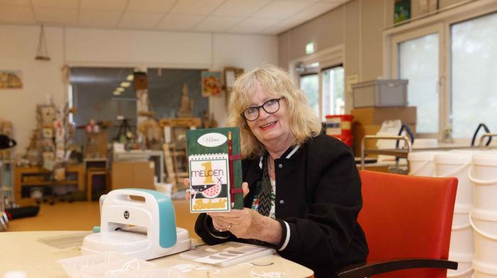 Mevrouw laat zien wat ze maakt bij de werkplaats van Korsakov Expertisecentrum Slingedael Mevrouw met blond haar en een zwarte bril zit aan een werktafel en laat haar zelfgemaakte project zien