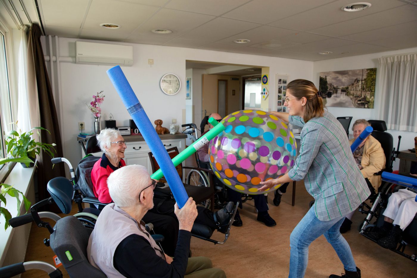 Bewegingsagoog Femke Bol doet bewegingsagogiek in verpleeghuis De Burcht Bewegingsagoog staat met een grote bal in een kring met ouderen als bewegingsagogiek in verpleeghuis van Lelie zorggroep