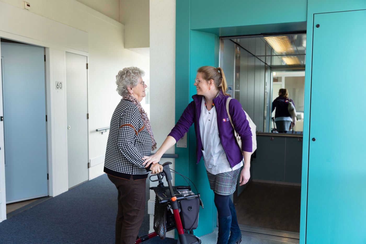 Cliënt met rollator bij lift zorgmedewerker vacature thuiszorg Zorgmedewerker gaat weer weg en cliënt is met de rollator meegelopen tot de lift