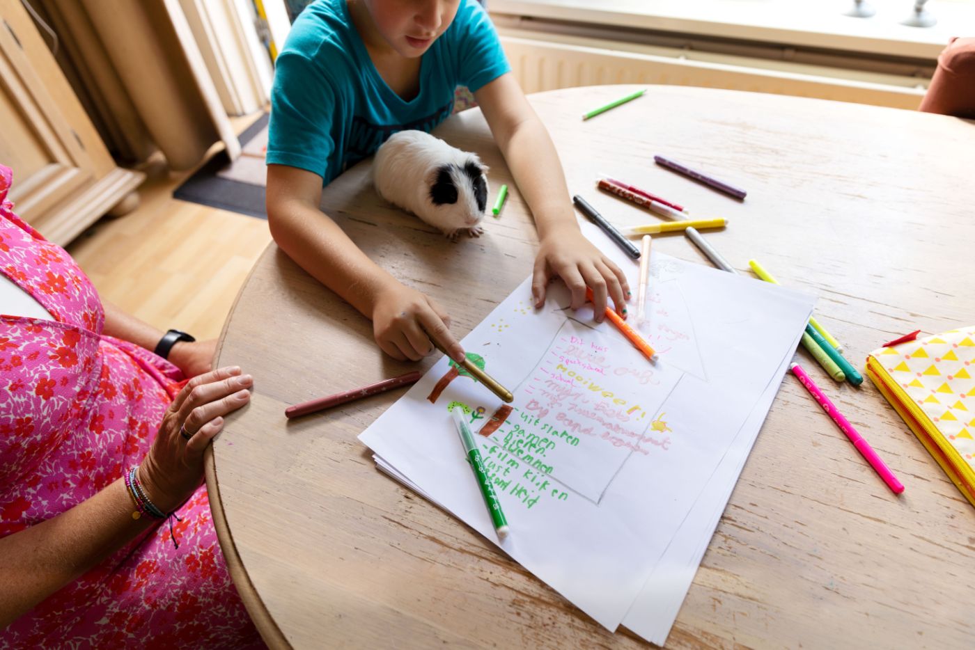 Hulpverlener client kind tekening op tafel in huis Kind en hulpverlener tekenen een huis op papier tijdens het begeleidingsgesprek