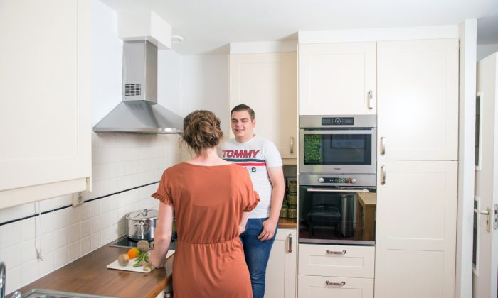 Hulpverlener en jongere cliënt in gesprek keuken Jongere client voert gesprek met hulpverlener in de keuken onder het koken